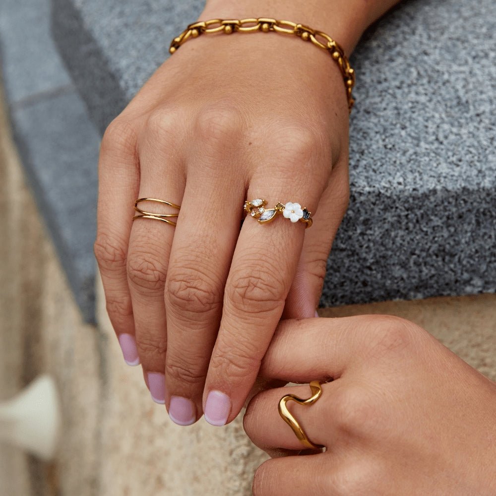 Anillo dorado con flor blanca de cristal